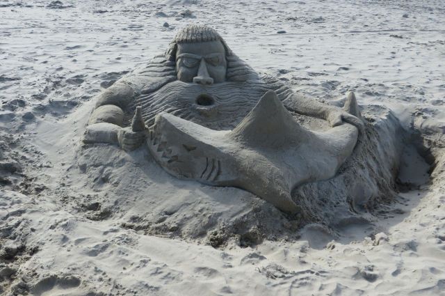 A very creative man built this sand sculpture. His description of it? Neptune is protecting his beer from the shark!