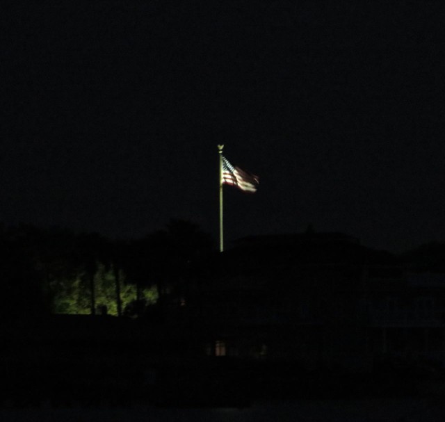 The illuminated United States flag on shore glowed in the early morning.