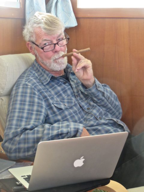 Al studying weather rand current forecasts on the computer. THat's a cookie, not a cigar. 