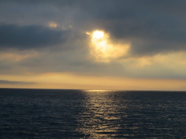 The sun is peaking through the clouds and waking up the ocean.